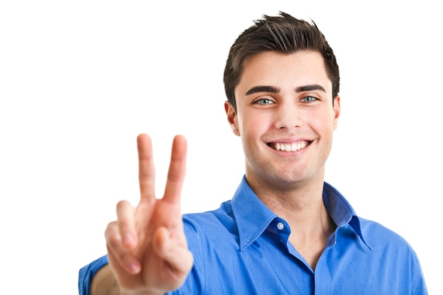 Smiling young businessman showing victory gesture