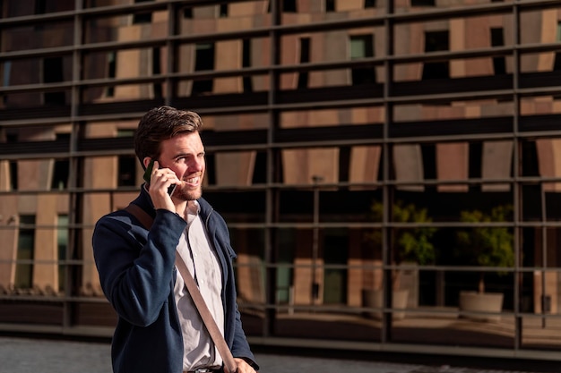 Smiling young businessman walking talking by phone