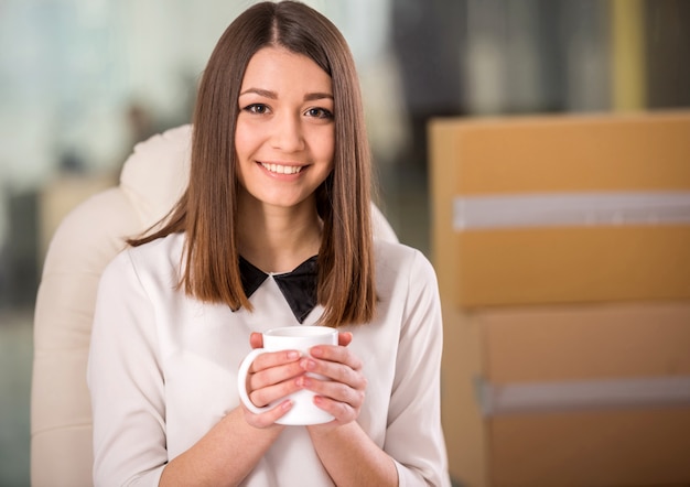 Smiling young businesswoman drinking tea in office.