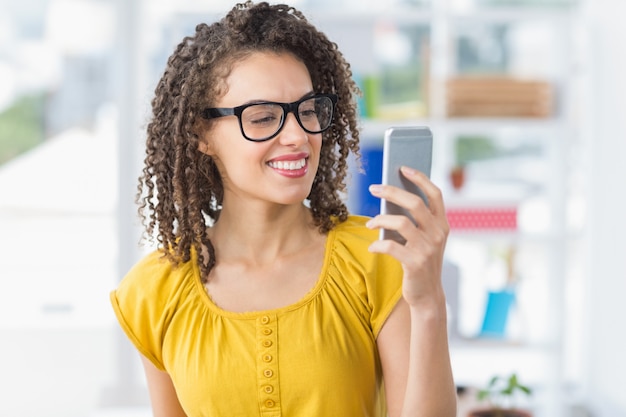 Smiling young businesswoman sending a text