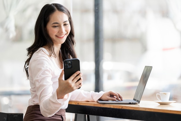 Smiling young businesswoman using smart phone sitting at home office