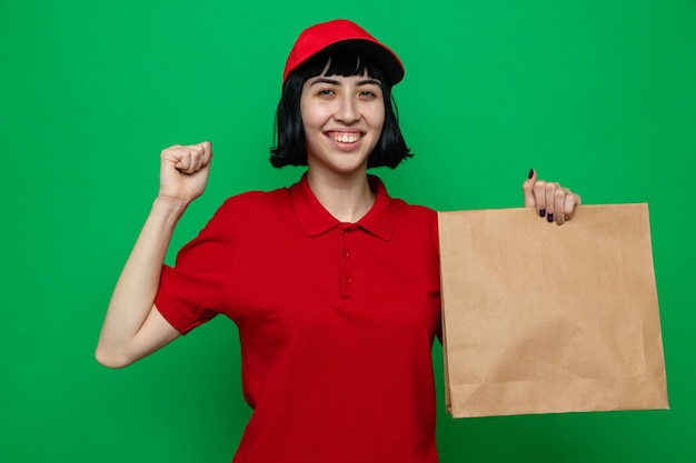 Smiling young caucasian delivery girl holding food packaging and keeping fist