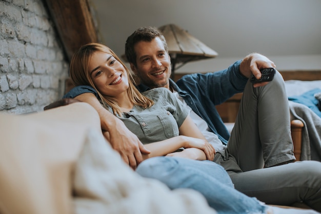 Smiling young couple relaxing and watching TV at home