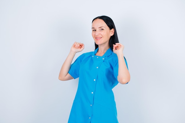 Smiling young doctor is looking at camera by holding up her hands on white background