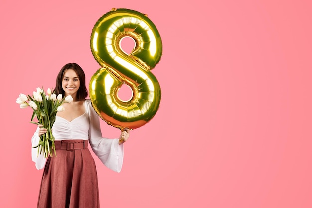 Smiling young european lady hold bouquet of flowers balloon number 8 enjoy spring holiday