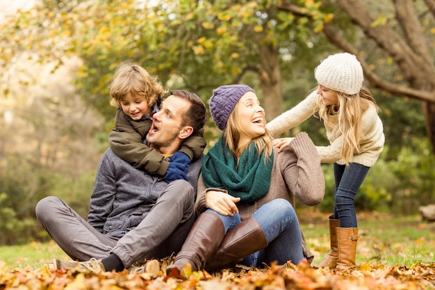 Smiling young family sitting in leaves