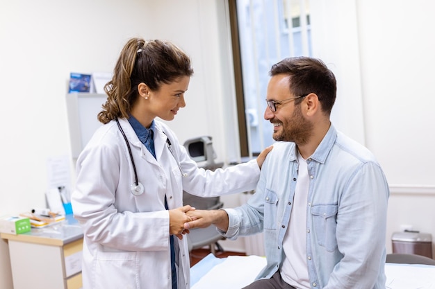 Smiling young female doctor shake hand close health insurance deal with elderly patient at consultation in hospital Happy woman GP handshake greeting get acquainted with man in clinic