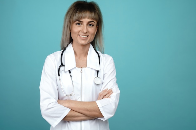 Smiling young female doctor with a stethoscope standing on a blue space