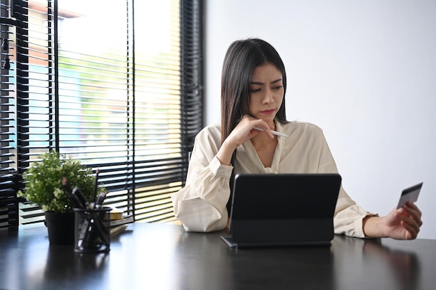 Smiling young female holding credit card and using laptop Online shopping ecommerce concept