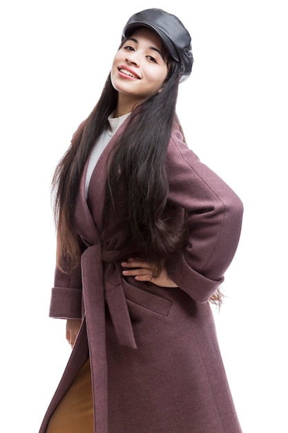 Smiling young girl in an elegant winecolored autumn coat and a black leather cap Pretty brunette with long hair Comfortable walks in the cold season Isolated on a white background Vertical