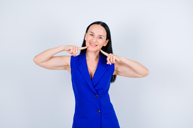 Smiling young girl is showing her smile with forefingers on white backgroundxDxA