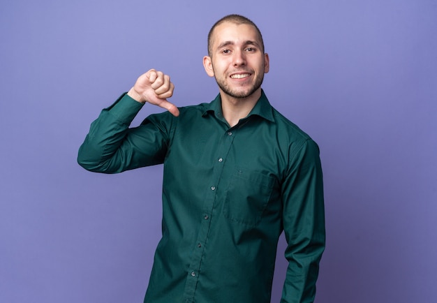 Smiling young handsome guy wearing green shirt points at himself 