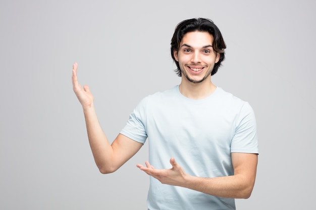 smiling young handsome man looking at camera showing empty hands isolated on white background