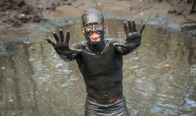 Smiling young latin american man getting green clay treatment