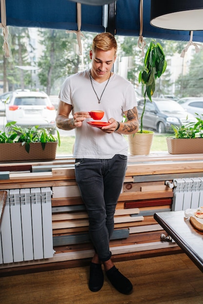 Smiling young man appreciating his cup of coffee looking at it