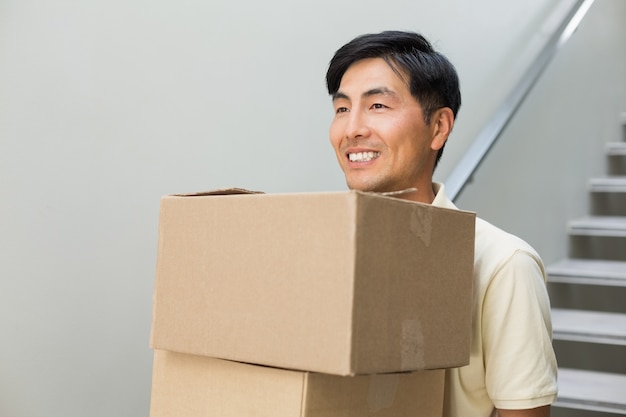 Smiling young man carrying boxes