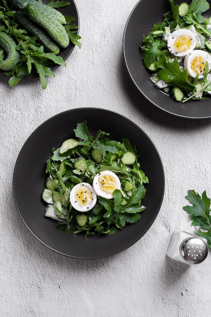 Smiling young  man cooking salad, cutting fresh vegetables in modern black kitchen