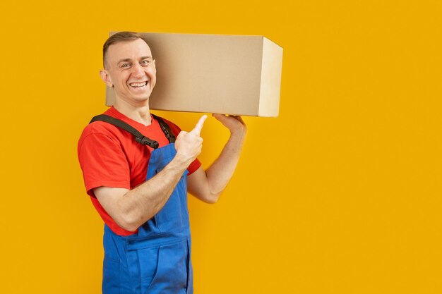 Smiling young man holding paper box Young delivery man Isolated on yellow background Copy space mock up