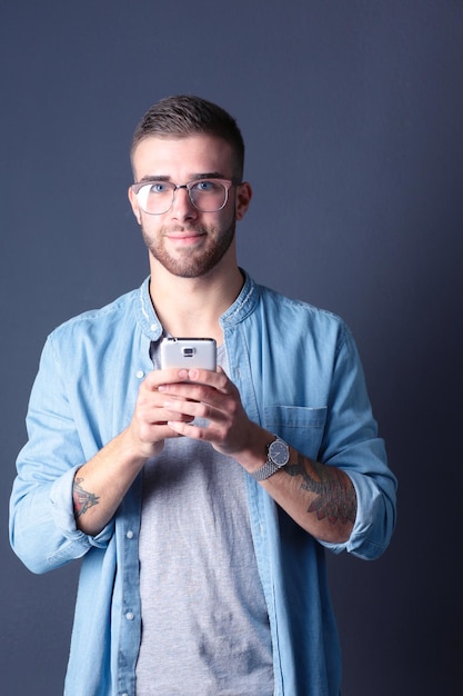 Smiling young man holding phone while text messaging