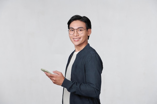 Smiling young man looking at his smart phone while text messaging isolated on white background