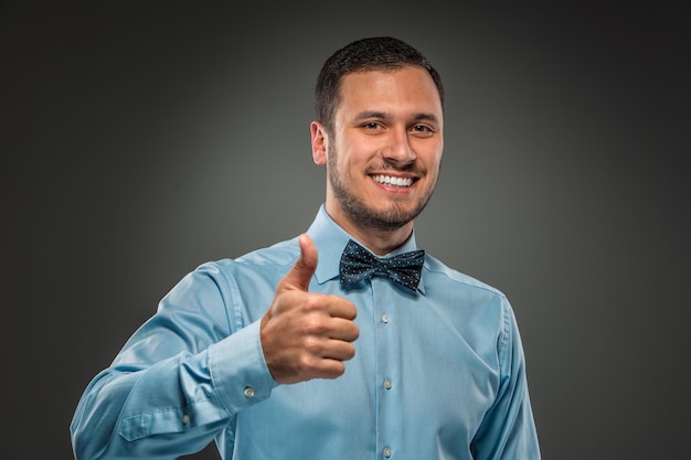 Smiling young man making the ok thumbs up hand sign