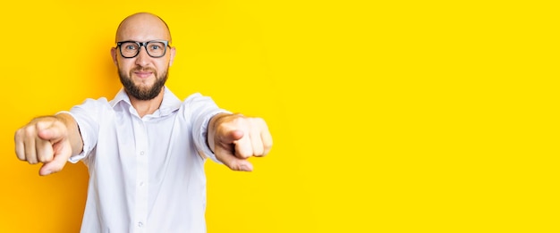 Smiling young man pointing fingers at viewer on yellow background Banner