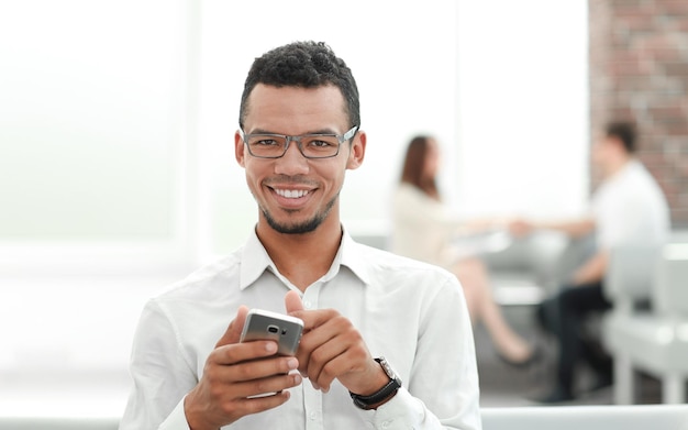 Smiling young man reading sms on his smartphone