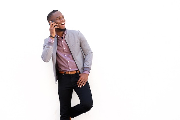 Smiling young man talking on mobile phone against white background