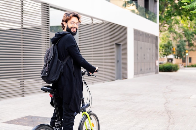 Smiling young man walking with a folding bike