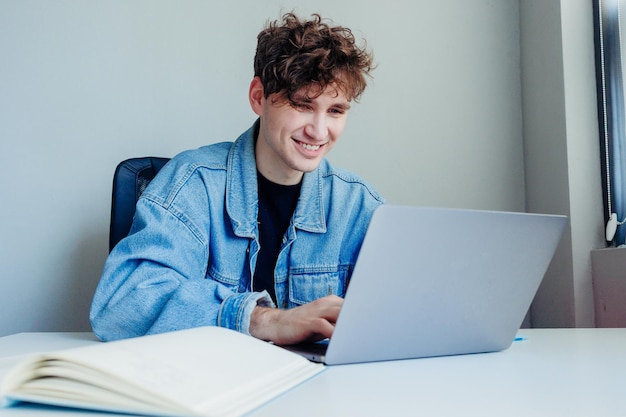 Smiling young man working on his laptop Freelancer in the office or at home working