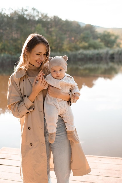 Smiling young mother playing with baby boy wear casual clothes posing over nature background in sun