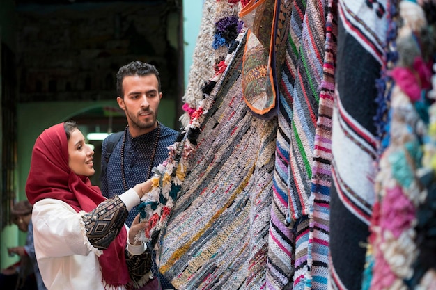 Photo smiling young muslim couple shopping carpets in a textile store