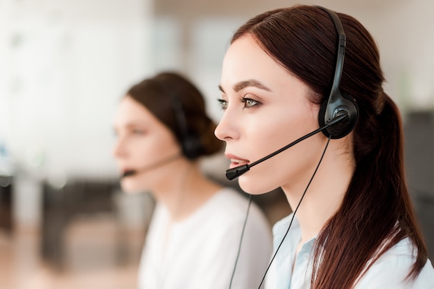 Smiling young office worker with a headset  answering in a call center