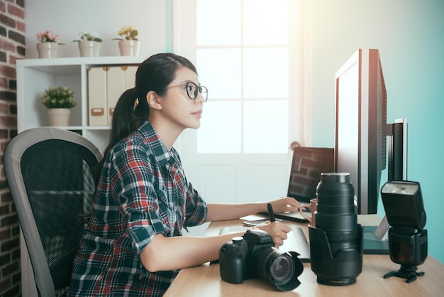 smiling young picture company office worker girl using digital pad editing and holding technology pen looking at computer retouch business photo.