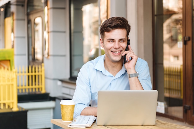 Smiling young stylish man in shirt talking on mobile phone