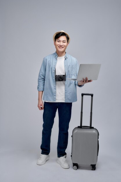 Smiling young traveler tourist man in summer clothes hat working on laptop pc computer booking hotel