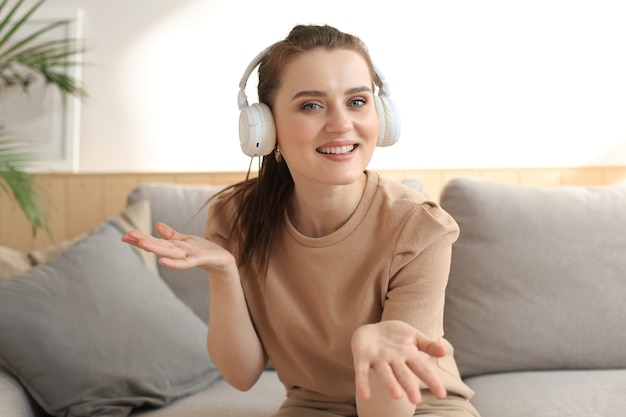 Smiling young woman blogger influencer working at home. Girl talking at web camera, making videochat or conference call, female recording vlog.