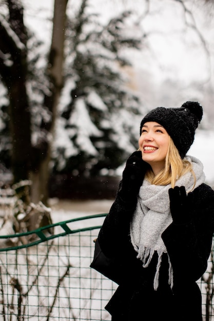 Smiling Young Woman in Cozy Clothing using mobile phone on winter day