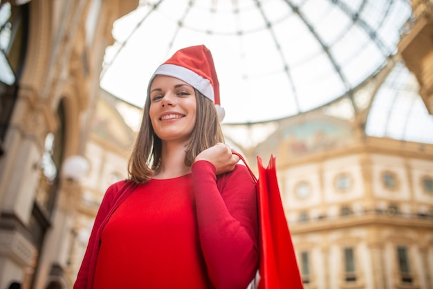 Smiling young woman dressed in red doing Christmas shopping in Milan, Italy