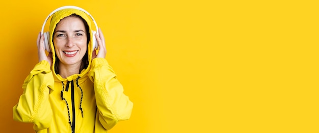 Smiling young woman in headphones listening to music on a yellow background Banner