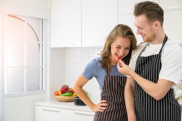 Smiling young woman holding bowl with fresh vegetables in the kitchen