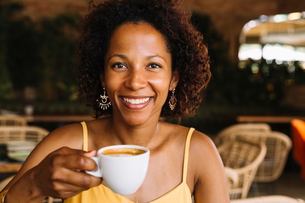 Smiling young woman holding cup of coffee in hand