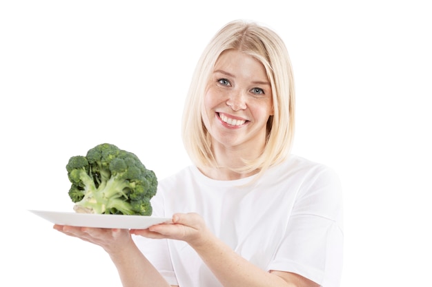 Smiling young woman holding a plate of broccoli in her hands. Vegetarianism and raw food diet. Health and proper nutrition. Isolated over white background.