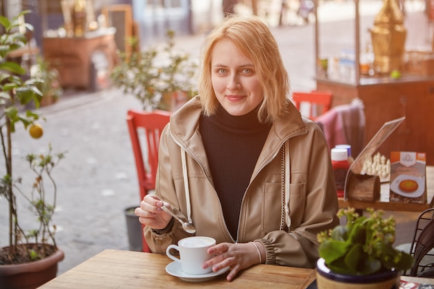 Smiling young woman is relaxing in street cafe in Istanbul with cup of coffee