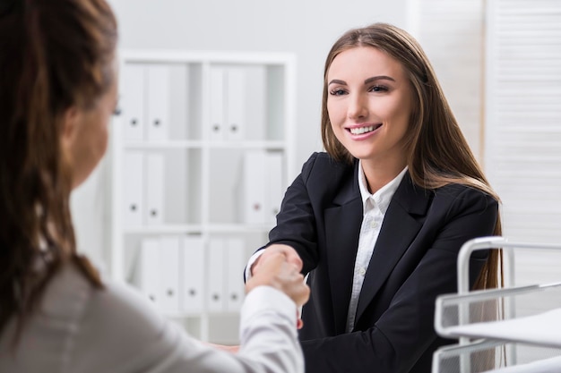 Photo smiling young woman is shaking hands