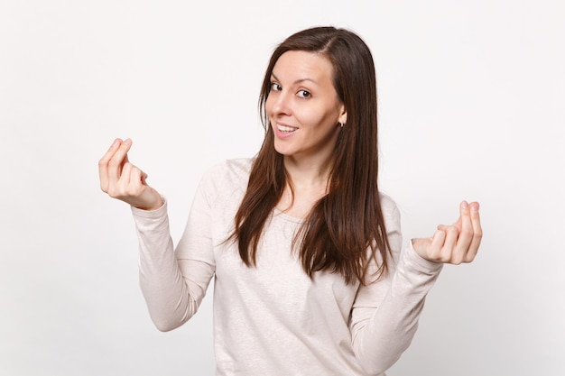 Smiling young woman in light clothes rubbing fingers, showing cash gesture asking for money isolated on white wall background in studio. People sincere emotions, lifestyle concept. Mock up copy space.