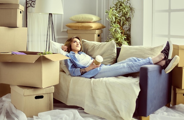 Photo smiling young woman lying on sofa in new apartment