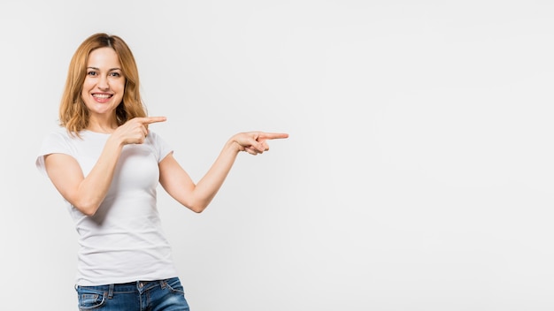 Smiling young woman pointing the fingers isolated on white background