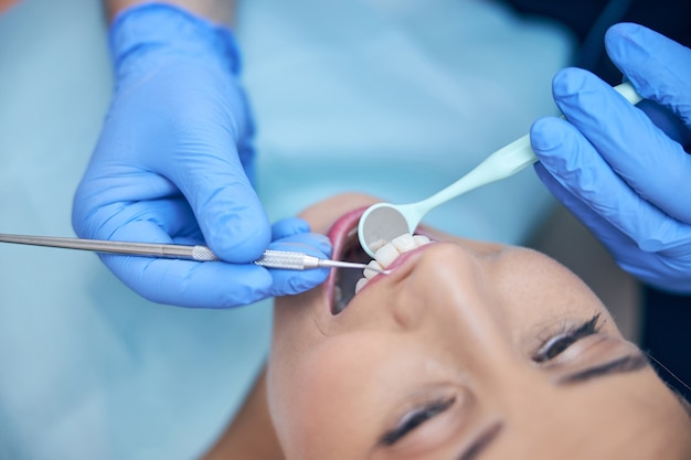 Smiling young woman during procedures in dental clinic