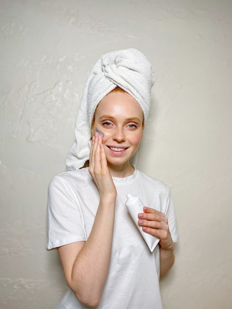 Smiling young woman puts a cosmetic mask on her face